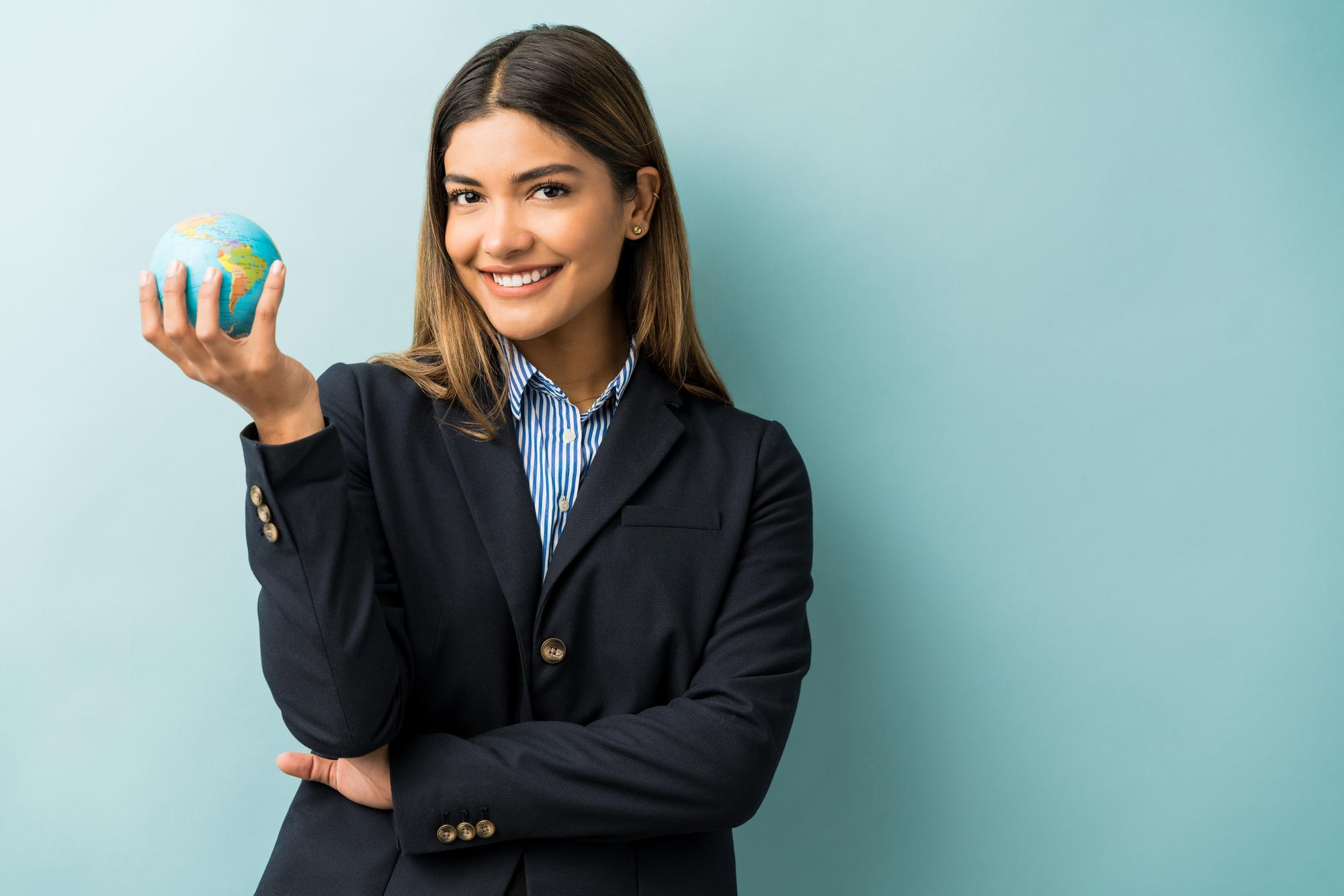 An advisor in a dark blazer holding a small globe, smiling