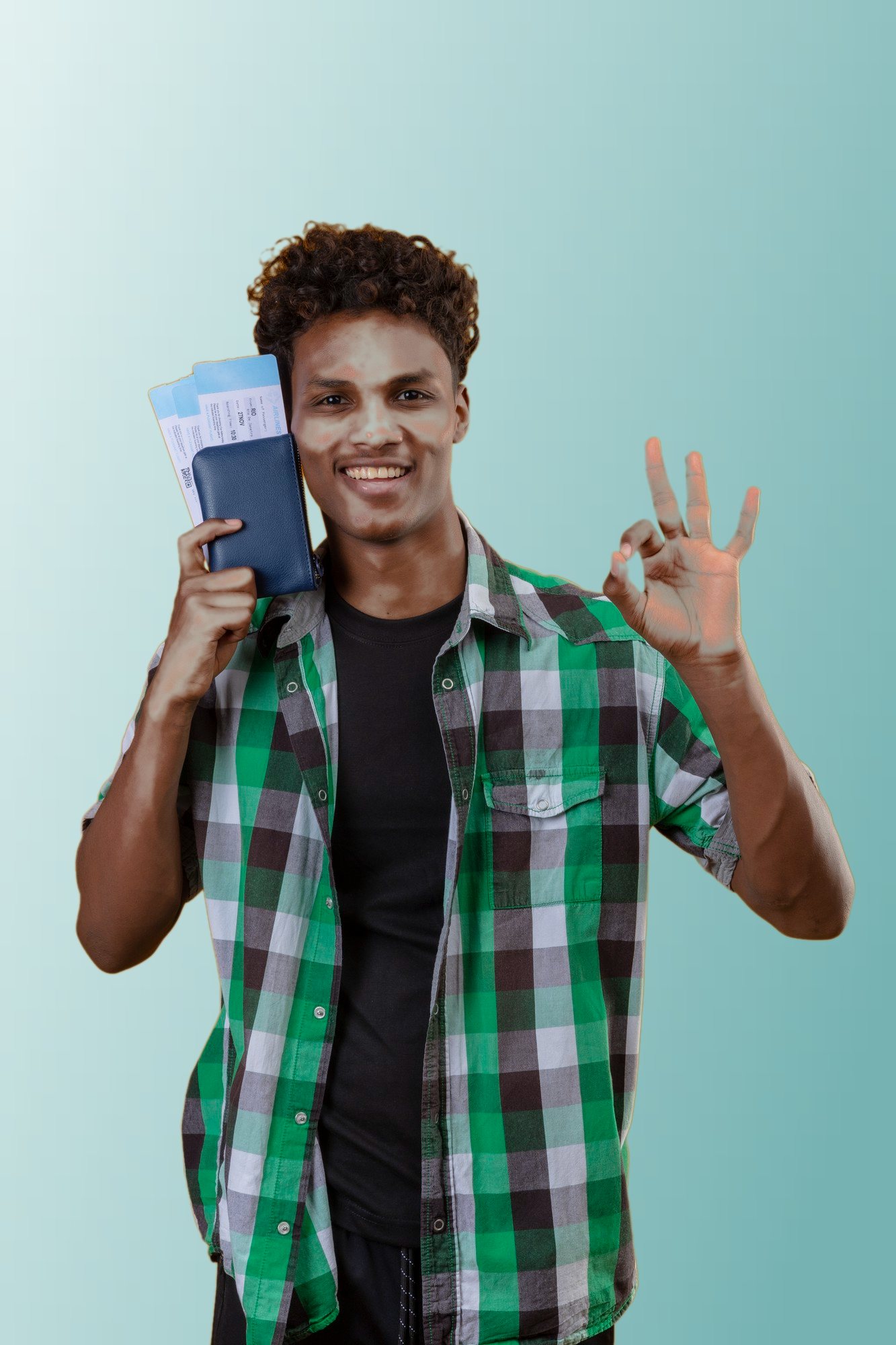 A smiling student holding a passport and boarding passes, making an OK sign